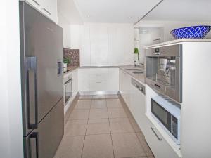 a kitchen with white cabinets and a stainless steel refrigerator at Stunning Ground Floor City Apartment 104 in Cairns