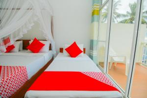 Onaro Beach View في ماتارا: غرفة نوم بسريرين ومخدات حمراء وبيضاء
