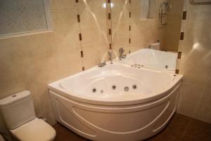 a white tub in a bathroom with a toilet at Bogemia Private Residence in Saratov