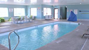 uma grande piscina com mesas e cadeiras num quarto em Holiday Inn Express Hotel & Suites Plainview, an IHG Hotel em Plainview