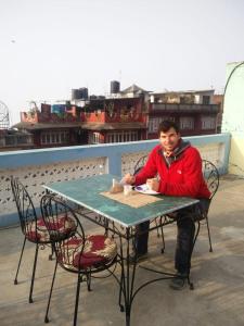 mężczyzna siedzący przy stole na balkonie w obiekcie Gorkha Chhen bed & breakfast w mieście Gorkhā