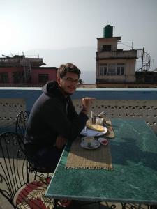 mężczyzna siedzący przy stole z talerzem jedzenia w obiekcie Gorkha Chhen bed & breakfast w mieście Gorkhā