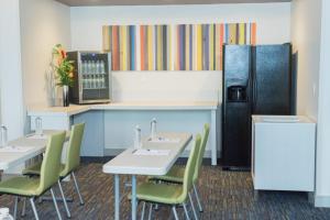een keuken met 2 tafels en een koelkast bij Holiday Inn Express Pascagoula-Moss Point, an IHG Hotel in Moss Point