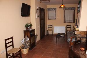 a living room with a tv and some chairs at Apartamentos La Plaza in Majaelrayo