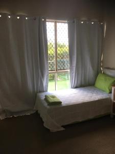 uma cama num quarto com uma janela em Accommodation on Westlake Mount Ommaney em Mount Ommaney