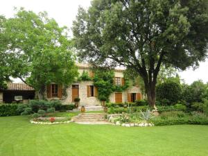 a stone house with a large yard with a tree at La Frandomière in Saint-Martin-de-Londres