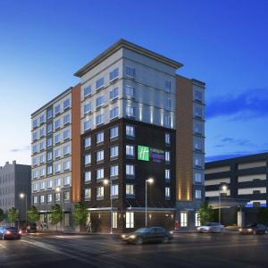 ルイスビルにあるHoliday Inn Express & Suites Downtown Louisville, an IHG Hotelの緑の看板が立つ高層ビル