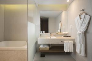 bagno con lavandino, vasca e specchio di Hidden Cliff Hotel and Nature a Seogwipo