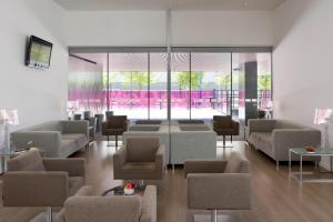 uma sala de espera com sofás, cadeiras e janelas em Holiday Inn Express Madrid Leganes, an IHG Hotel em Leganés