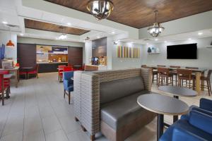 a restaurant with a couch and tables and a bar at Holiday Inn Express Tiffin, an IHG Hotel in Tiffin