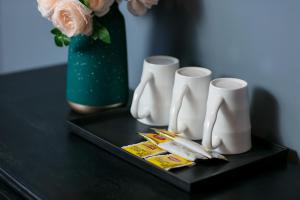 a black table with three white cups and a vase with flowers at Vientiane Boutique Hotel in Vientiane