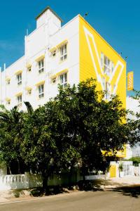 a yellow and white building with a tree in front of it at X by Bloom I Hebbal Manyata Park in Bangalore