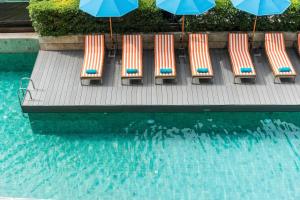 a row of chairs and umbrellas next to a swimming pool at Hotel Vista in Pattaya Central