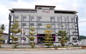 a large white building with trees in front of it at Salsa Resort Langkawi By Casa Loma in Pantai Cenang
