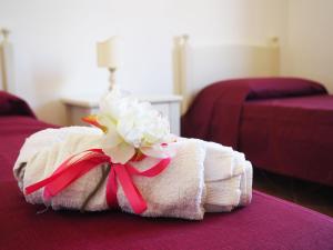 une serviette avec une fleur assise au-dessus du lit dans l'établissement Casa Vacanze De Grazia direttamente sul Mare, à Botricello