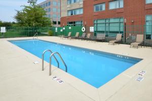 una grande piscina con sedie e un edificio di Elimwood Hotel, a Ramada by Wyndham a Maryland Heights