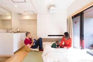 a group of people sitting on a bed in a room at Sakura Cross Hotel Akihabara in Tokyo