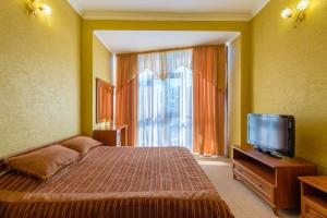 Schlafzimmer mit einem Bett und einem Flachbild-TV in der Unterkunft Hotel Feodosiya in Feodossija