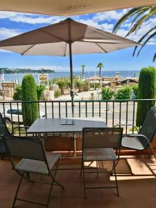 una mesa y sillas con una sombrilla en el balcón en Les Marines d'Agay Studio climatisé en Saint-Raphaël