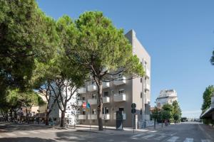 um edifício ao lado de uma rua com árvores em Hotel Iris ***S em Lido di Jesolo