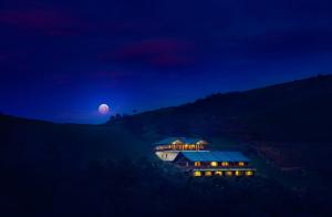 une maison sur une colline la nuit avec la lune dans l'établissement Destiny - The Farm Resort, à Ooty