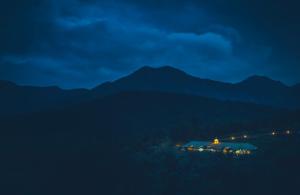 a night view of a house with mountains in the background at Destiny - The Farm Resort in Ooty