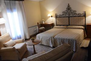 Habitación de hotel con cama y sofá en Hostal Rural Cumbres De Castilla en Mandayona