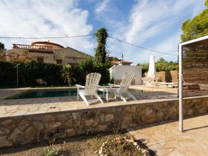 een patio met 2 stoelen, een tafel en een zwembad bij INNOUTHOME Chalet familiar con piscina privada numero u in L'Ametlla de Mar