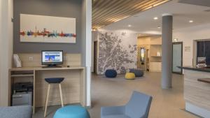 a living room with blue chairs and a desk with a computer at Holiday Inn Express München Messe, an IHG Hotel in Feldkirchen