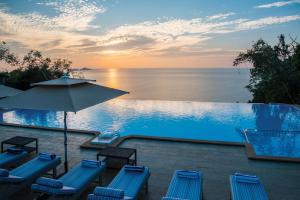 una piscina con sillas y una sombrilla y el océano en Cintacor Island Resort en Kārwār