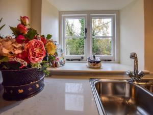 a kitchen sink with a vase of flowers on the counter at Archers in Winchcombe