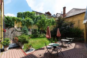 eine Terrasse mit Tischen und Sonnenschirmen in einem Garten in der Unterkunft Coroana Brasovului in Braşov