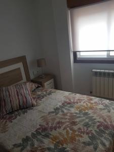 1 dormitorio con cama y ventana con manta de flores en Apartment in Fragoso street, very spacious and close to Samil., en Vigo