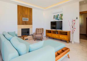 ein Wohnzimmer mit einem blauen Sofa und einem Fernseher in der Unterkunft Villa 2 Sleeps 4 Isolated Honeymoon-Villa Sardunya in Kaş