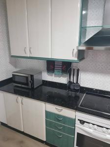 cocina con armarios blancos y microondas en Apartment in Fragoso street, very spacious and close to Samil., en Vigo