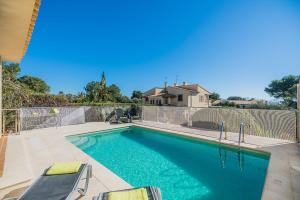 ein Swimmingpool mit Stühlen neben einem Zaun in der Unterkunft Vistamar 5A - Puerto de Alcudia in Alcúdia