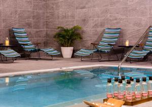 a swimming pool with chairs and a group of bottles of wine at Axel Hotel San Sebastián - Adults Only in Donostia-San Sebastián