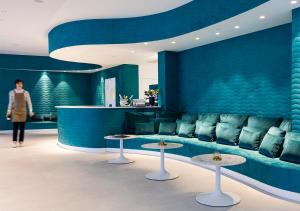 a woman standing in a room with a couch and tables at Axel Hotel San Sebastián - Adults Only in Donostia-San Sebastián