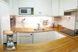 a kitchen with white cabinets and a sink at Apto. luminoso-6PAX-WIFI-15'/tren Plaza Catalunya in Sant Adria de Besos