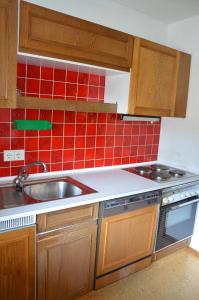 eine Küche mit einem Waschbecken und roten Wandfliesen in der Unterkunft Ferienhaus Dum in Leogang