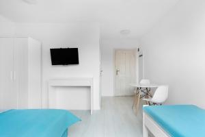 a white room with two beds and a tv on the wall at Apartamenty Góra in Wejherowo