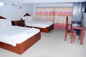 a bedroom with two beds and a table and a chair at Khmer Village Guesthouse in Phnom Penh