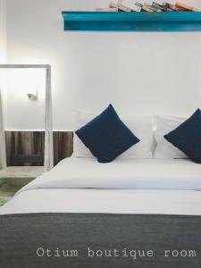 a white bed with blue pillows and a mirror at Otium Boutique Room in Pai