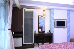 um quarto com uma secretária, uma cama e uma televisão em Lang Qin Hai Inn em Kenting