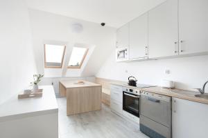 a white kitchen with white cabinets and a wooden table at Apartamenty Góra in Wejherowo