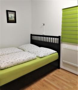 a bed with a black frame and a green window at Ferienwohnung J10, Playmobil Funpark Zirndorf Nürnberg in Zirndorf