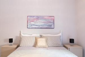 a bedroom with a white bed with a painting above it at Stylish, comfy apartment by Konnect, Corfu city center in Corfu