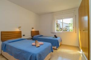 um quarto com 2 camas azuis e uma janela em Villa Los Robles em Begur