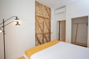 a bedroom with a white bed and a brick wall at Montebelo Lisbon Downtown Apartments in Lisbon