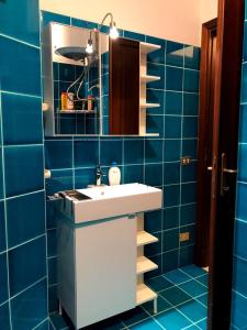 Baño de azulejos azules con lavabo y espejo en Citai Hill, en San Teodoro